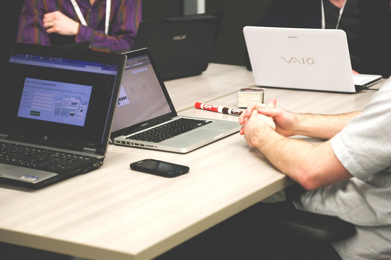 Colleghe e colleghi al tavolo con laptop e documenti